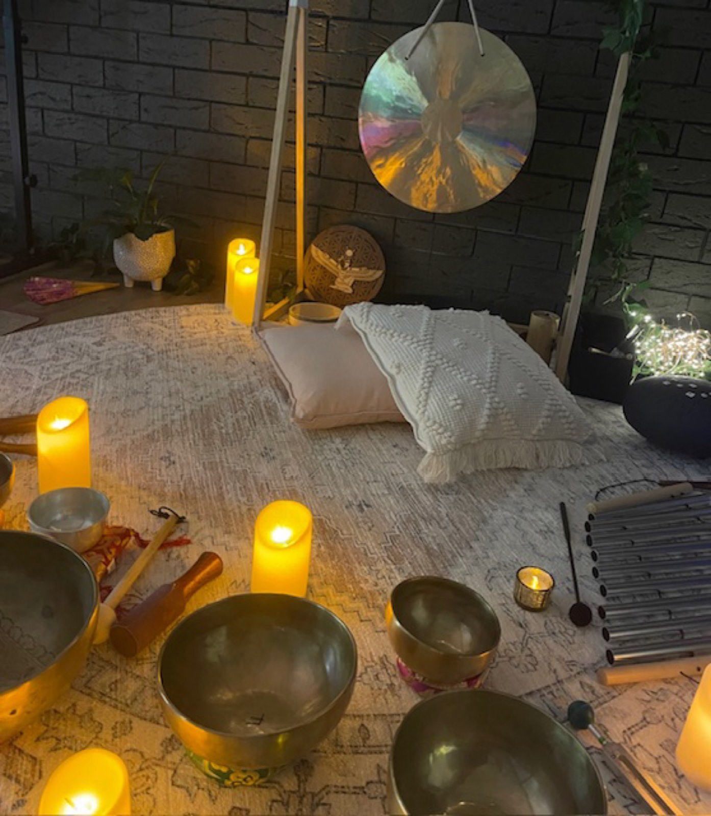 Crystal singing bowls and candlelight set out on the studio floor for a sound bath