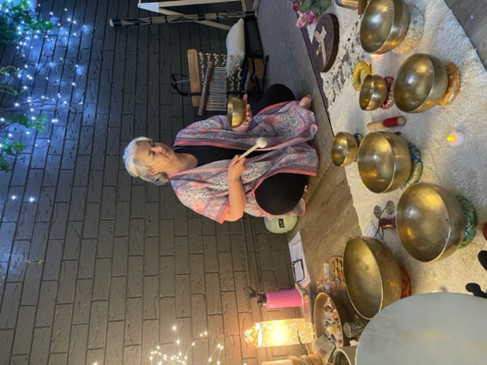 Sara playing the bowls by candlelight during a sound bath
